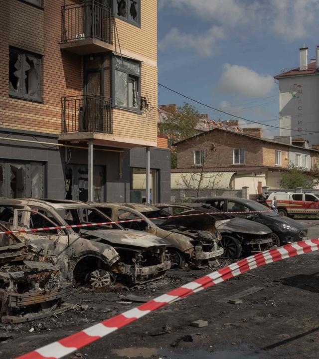 Ausgebrannte Autos vor einem beschädigten Wohngebäude nach russischen Drohnen- und Raketenangriffen in Kiew.