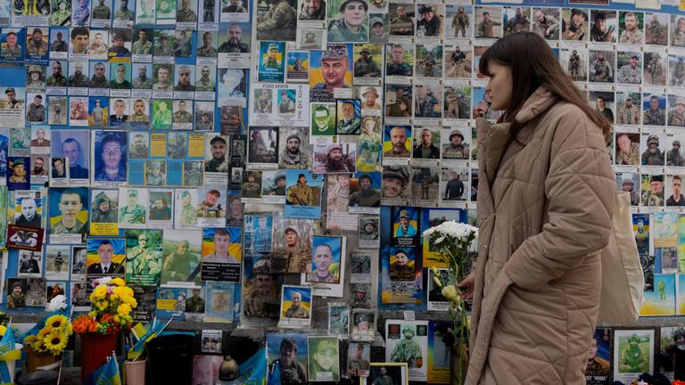 Eine Frau mit Blumen in der Hand gedenkt am 24. Februar 2026 an der Gedenkmauer den Gefallenen der Ukraine in Kiew, während die Ukraine den vierten Jahrestag des russischen Einmarsches erinnert.