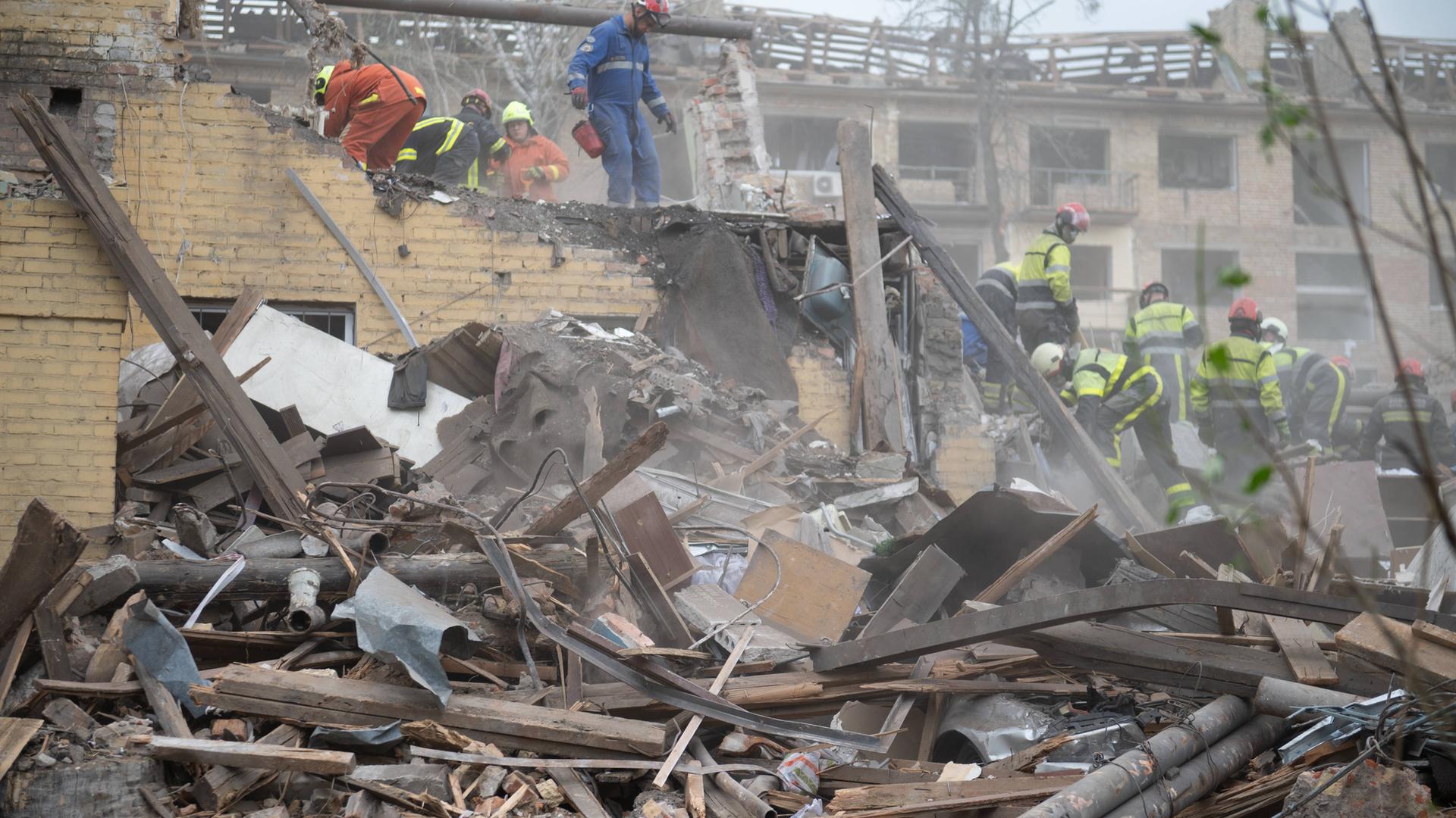 Ein zerstörtes Haus in Kiew nach einem russischen Luftangriff und Rettungskräfte.