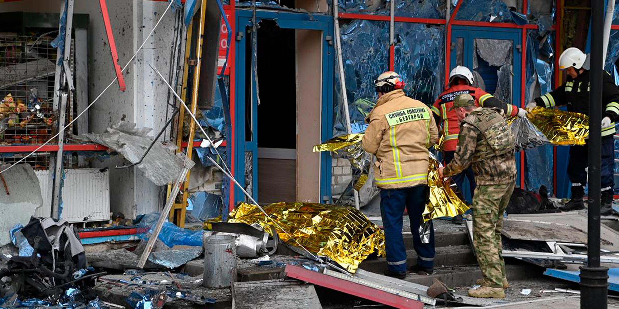 Auf diesem vom Telegram-Kanal des Gouverneurs der Region Belgorod veröffentlichten Foto stehen Feuerwehrleute vor einem beschädigten Gebäude in Belgorod, Russland