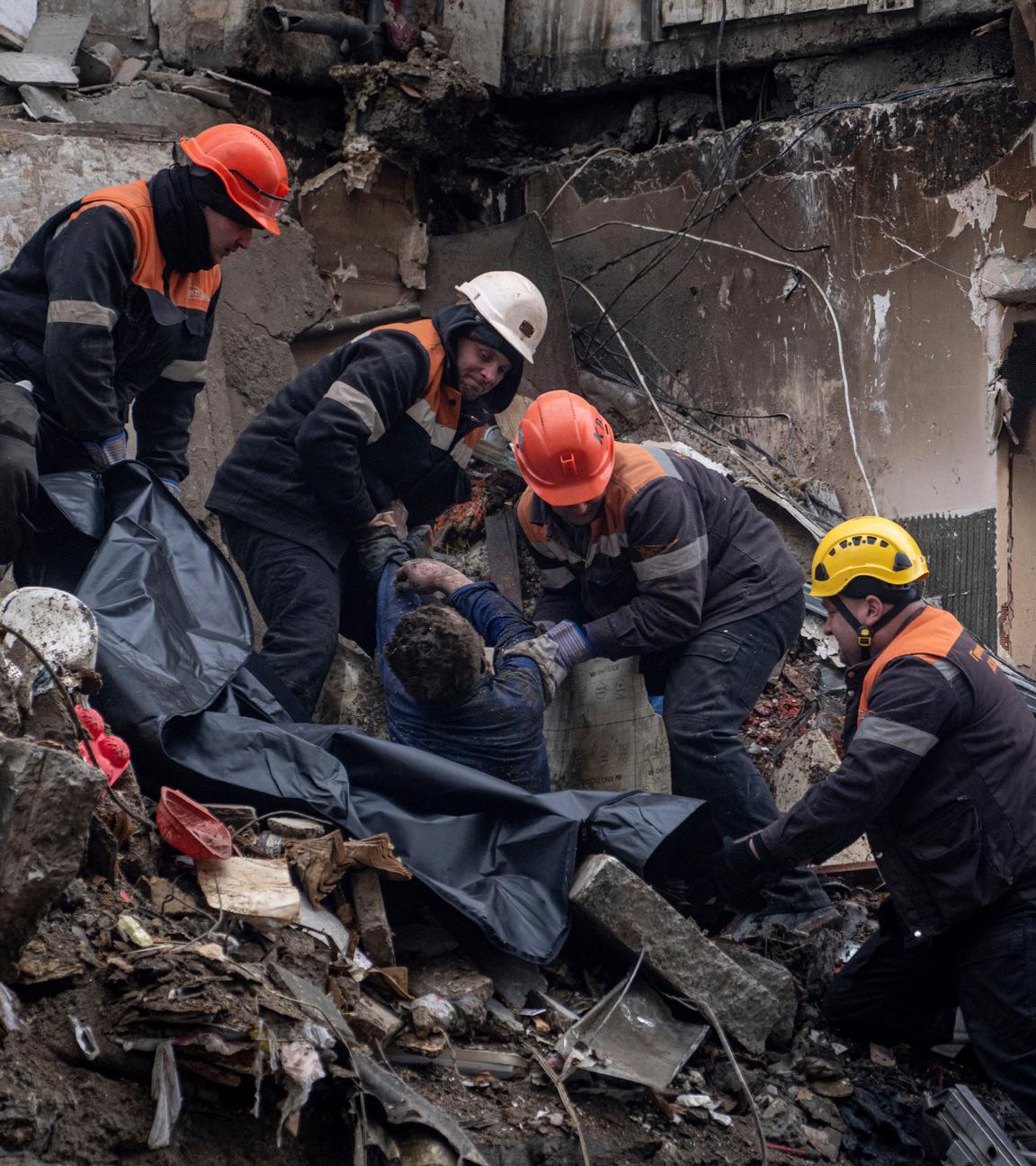 Rettungskräfte tragen den Körper eines Toten aus einem zerstörten Wohnhaus in Dnipro, Ukraine.