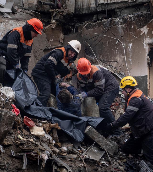 Rettungskräfte tragen den Körper eines Toten aus einem zerstörten Wohnhaus in Dnipro, Ukraine.