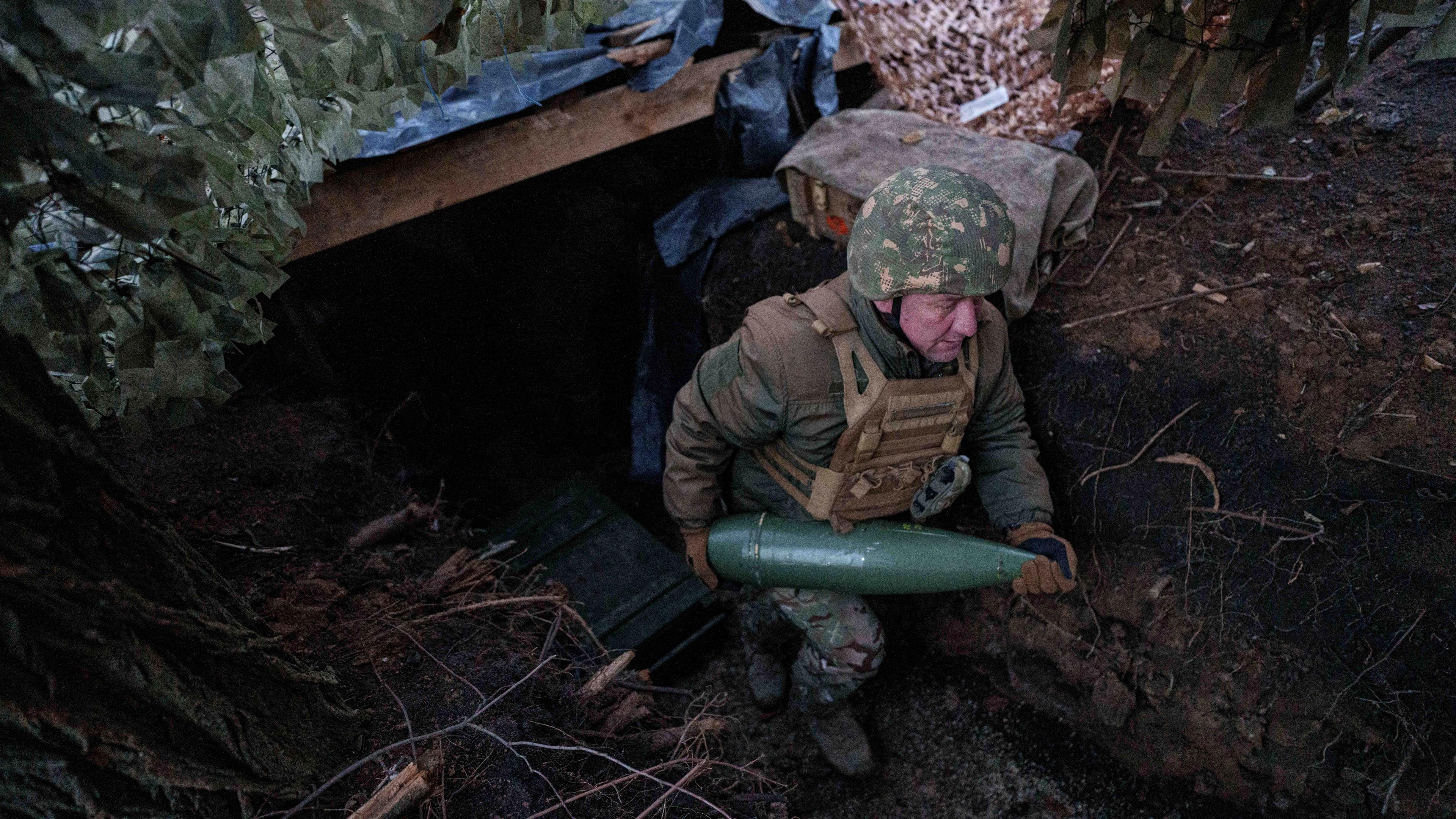Ein ukrainischer Soldat der 14. Brigade der Nationalgarde "Tscherwona Kalyna" trägt eine Artilleriegranate, bevor er auf russische Stellungen an der Frontlinie in Richtung Pokrowsk, Region Donezk, schießt.