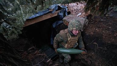 Ein ukrainischer Soldat der 14. Brigade der Nationalgarde "Tscherwona Kalyna" trägt eine Artilleriegranate, bevor er auf russische Stellungen an der Frontlinie in Richtung Pokrowsk, Region Donezk, schießt.