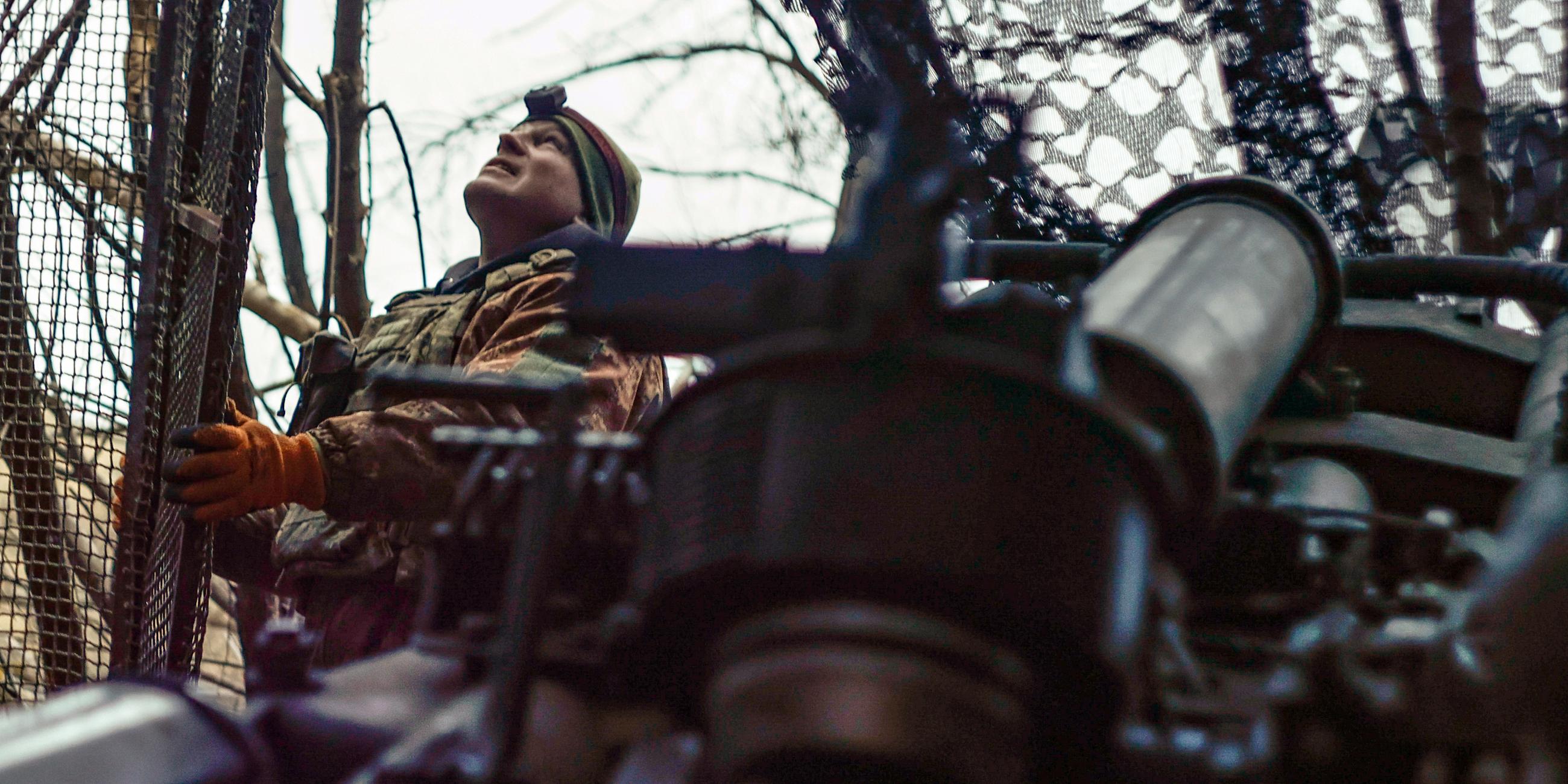 Ein ukrainischer Soldat schaut in den Himmel und sucht nach russischen FPV-Drohnen, während er sich darauf vorbereitet, eine Haubitze M777 auf russische Stellungen an der Frontlinie in der Nähe von Donezk abzufeuern.