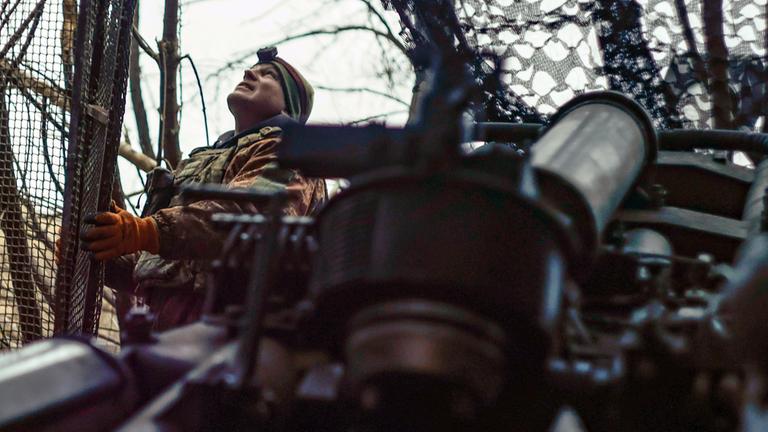 Ein ukrainischer Soldat schaut in den Himmel und sucht nach russischen FPV-Drohnen, während er sich darauf vorbereitet, eine Haubitze M777 auf russische Stellungen an der Frontlinie in der Nähe von Donezk abzufeuern.