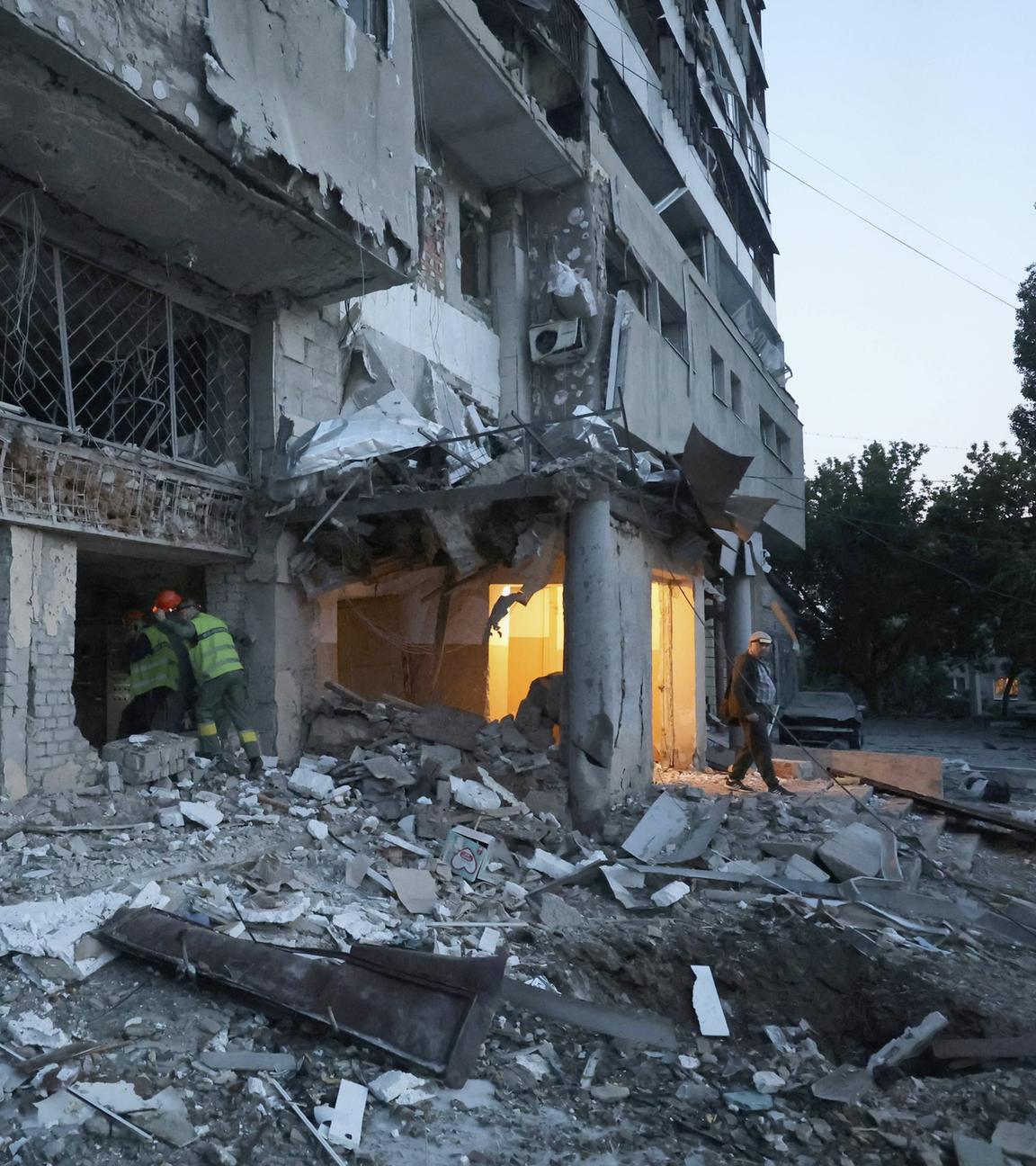 Städtische Angestellten betreten einen zerstörten Wohnblock in Charkiw.