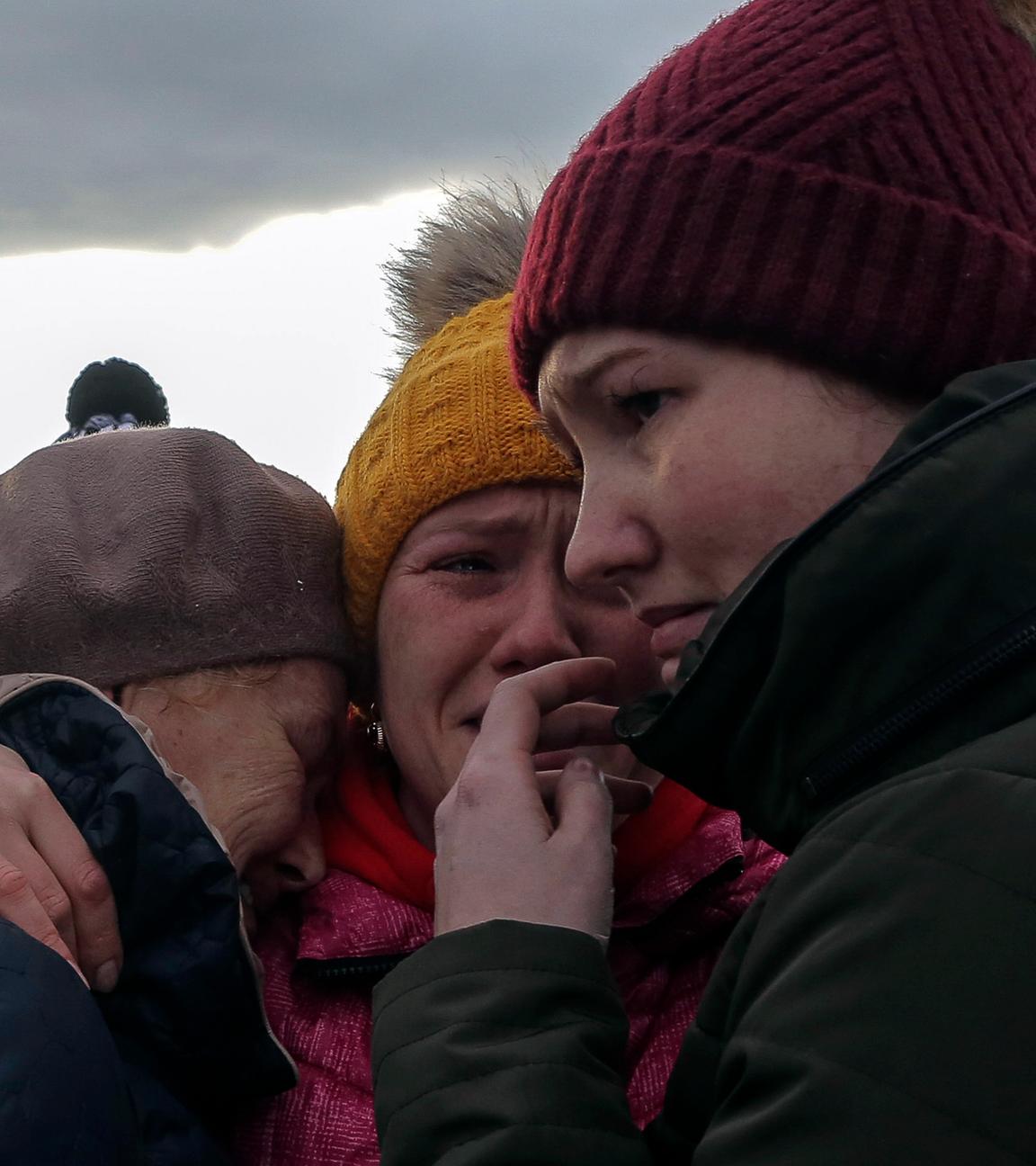 Drei geflüchtete ukrainische Frauen umarmen sich und weinen