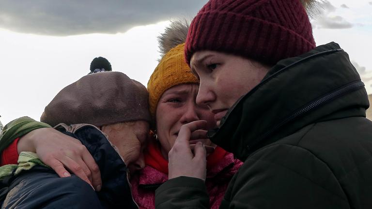 Drei geflüchtete ukrainische Frauen umarmen sich und weinen