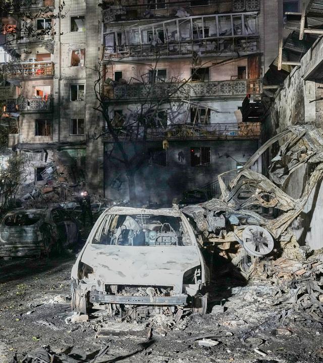 Ukraine, Kiew: Anwohner gehen nach einem russischen Raketenangriff in Kiew, Ukraine, zwischen den Trümmern. Archivbild