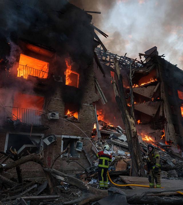 Ukraine, Kiew: Rettungskräfte löschen ein Feuer in einem Wohnhaus, das nach einem russischen Angriff in Kiew zerstört wurde.
