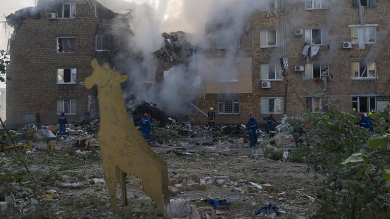 Rettungskräfte suchen unter Trümmern eines Wohnhauses nach Menschen. 