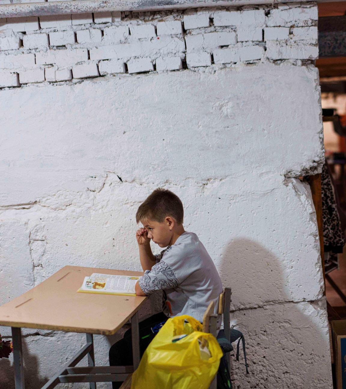 Ukraine, Bobryk Oblast Kiew: Ein Schüler hört einem Lehrer bei einer Unterrichtsstunde im Keller eines städtischen Gebäudes während des ersten Schultages zu. 