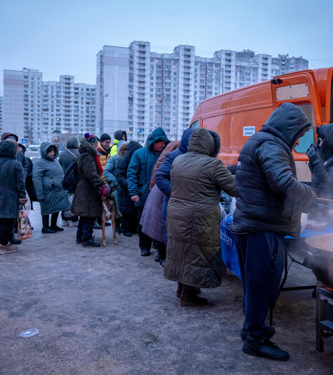 Ukraine, Kiew: Menschen, warten in einem Wohnviertel auf kostenlose warme Mahlzeiten.