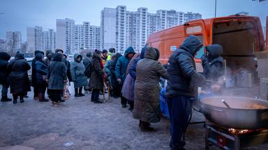 Ukraine, Kiew: Menschen, warten in einem Wohnviertel auf kostenlose warme Mahlzeiten.