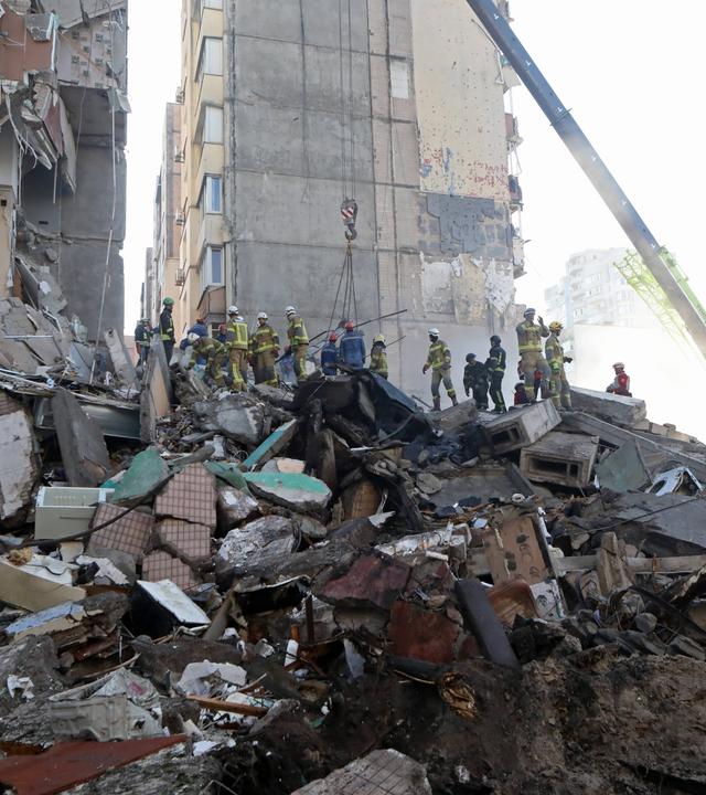 Rettungskräfte des staatlichen Rettungsdienstes räumen am 14. Mai 2026 in Kiew (Ukraine) Trümmer an einem neunstöckigen Wohnblock beiseite, der durch einen russischen Raketen- und Drohnenangriff beschädigt wurde. 