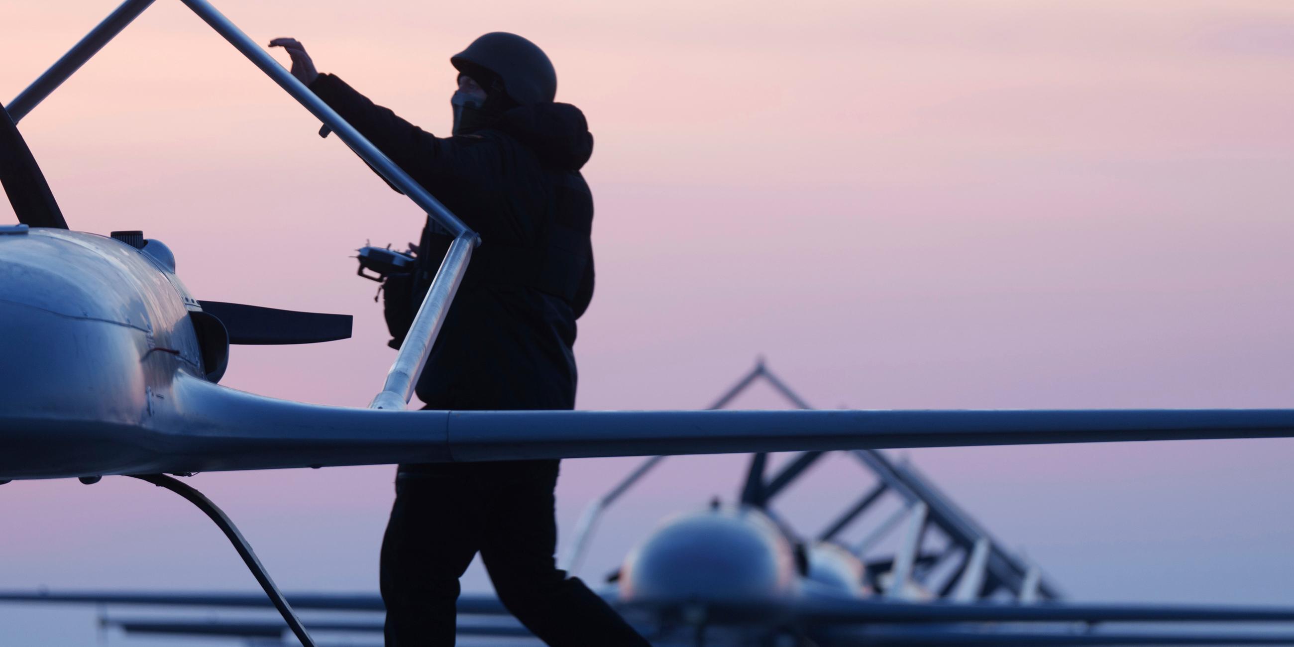 Ein Soldat in der Morgendämmerung vor dem Hintergrund zahlreicher Drohnen.