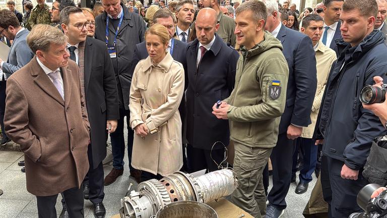 Der deutsche Außenminister Johann Wadephul (l-r, CDU), die EU-Außenbeauftragte Kaja Kallas und der französische Außenminister Jean-Noel Barrot lassen sich den Antrieb einer russischen Shahed-Drohne zeigen.