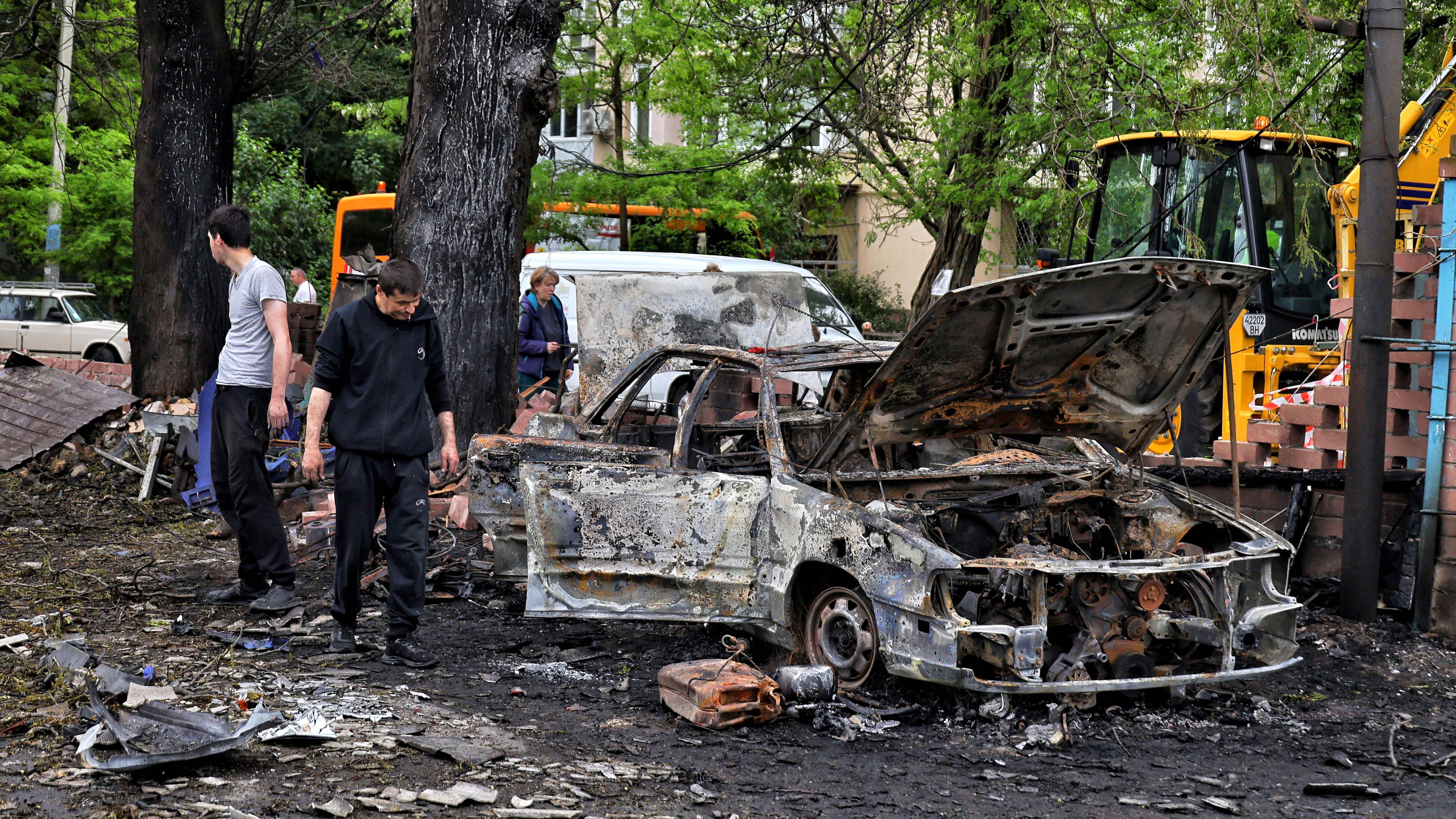 Menschen stehen neben ausgebrannten Autos nach einem nächstlichen Luftangriff auf die ukrainische Stadt Odessa.