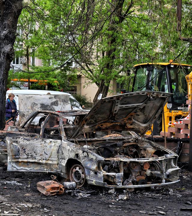 Menschen stehen neben ausgebrannten Autos nach einem nächstlichen Luftangriff auf die ukrainische Stadt Odessa.