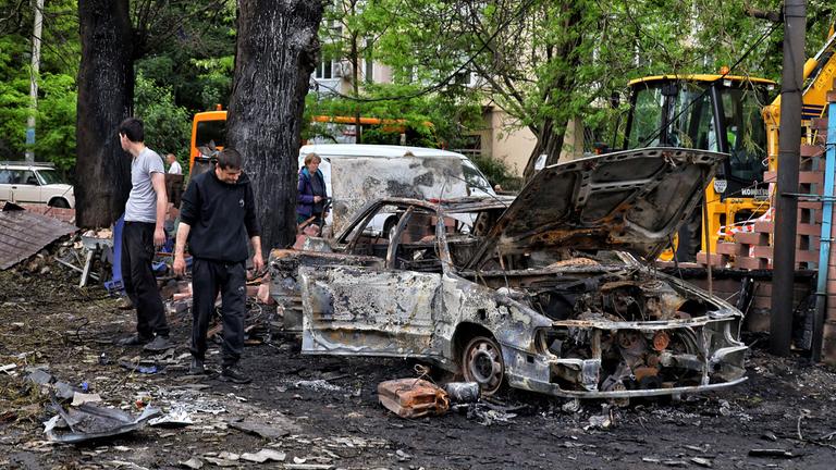 Menschen stehen neben ausgebrannten Autos nach einem nächstlichen Luftangriff auf die ukrainische Stadt Odessa.