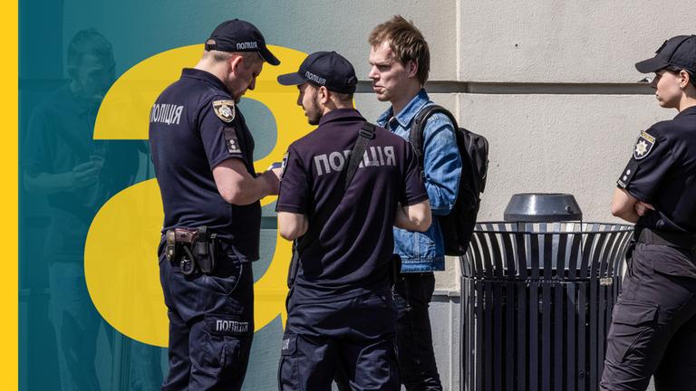 Polizisten kontrollieren die Ausweisdokumente junger Männer in Dnipro