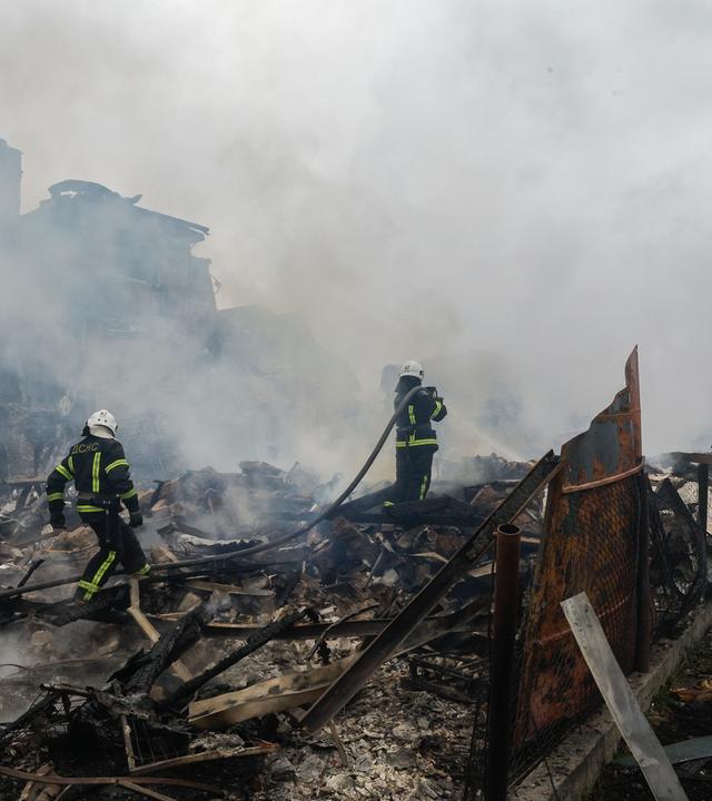 Zusammengestürzte Gebäude und Feuerwehrmänner, nach massiven Luftangriffen