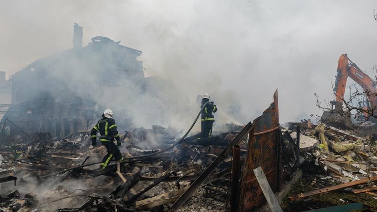 Zusammengestürzte Gebäude und Feuerwehrmänner, nach massiven Luftangriffen