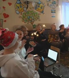 Nikolausfeier mit mehreren Personen in einem Wohnzimmer, die Menschen haben Wunderkerzen in der Hand.