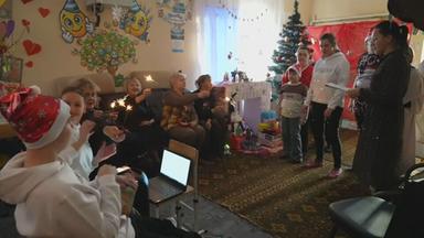 Nikolausfeier mit mehreren Personen in einem Wohnzimmer, die Menschen haben Wunderkerzen in der Hand.