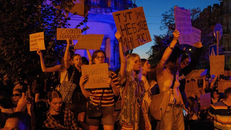 Mehrere Demonstranten halten in Kiew Plakate in die Luft.