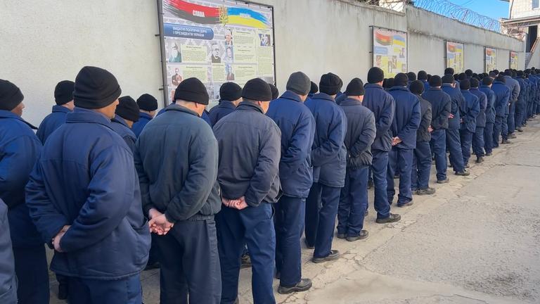 russische Kriegsgefangene stehen in einheitlicher Kleidung und in Reihen in deinem ukrainischen Gefangenenlager