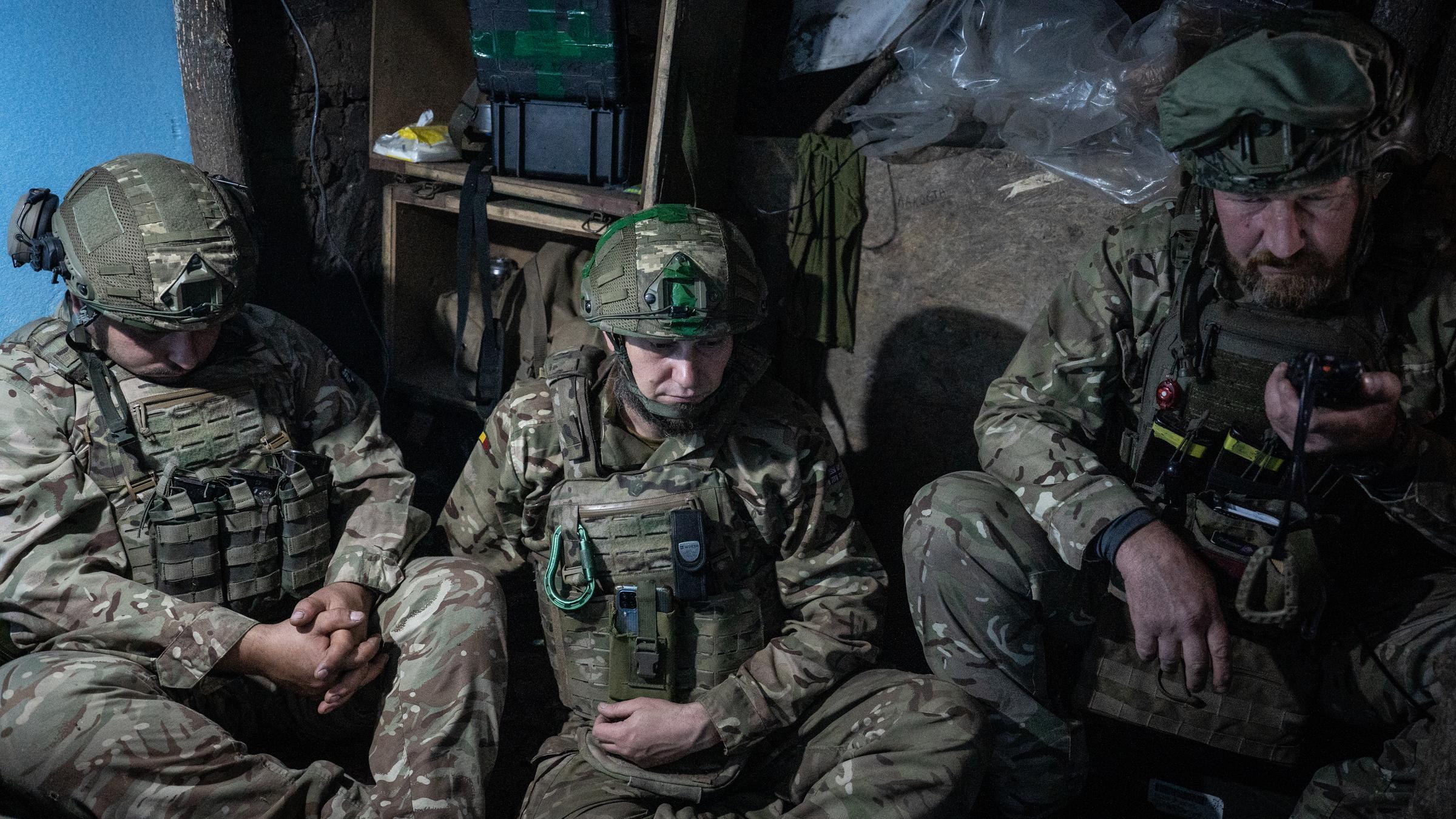Drei Soldaten sitzen in einem Graben.