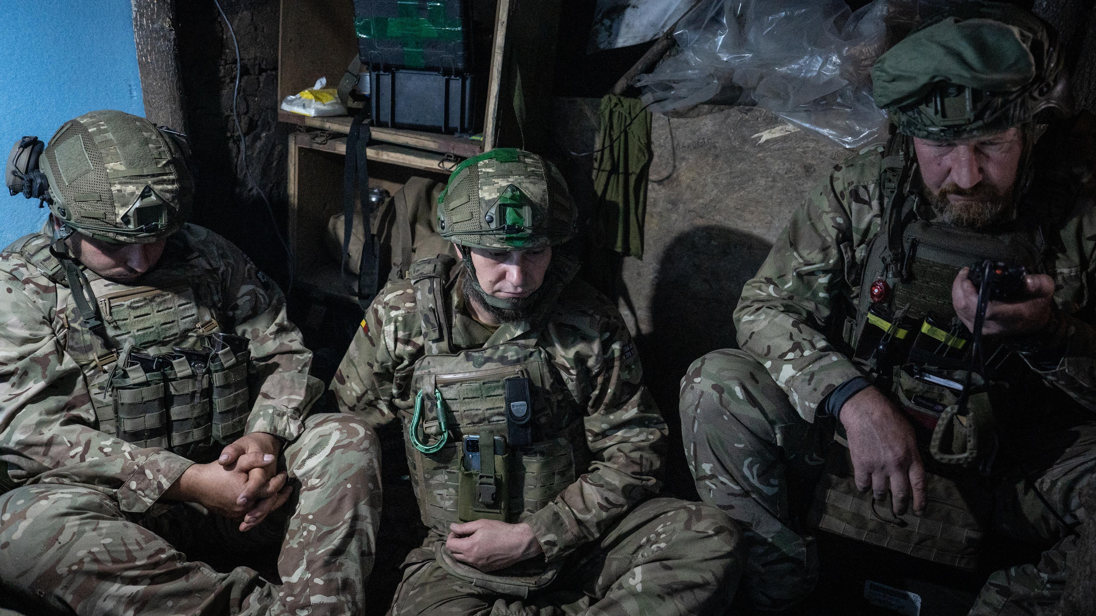 Drei Soldaten sitzen in einem Graben.