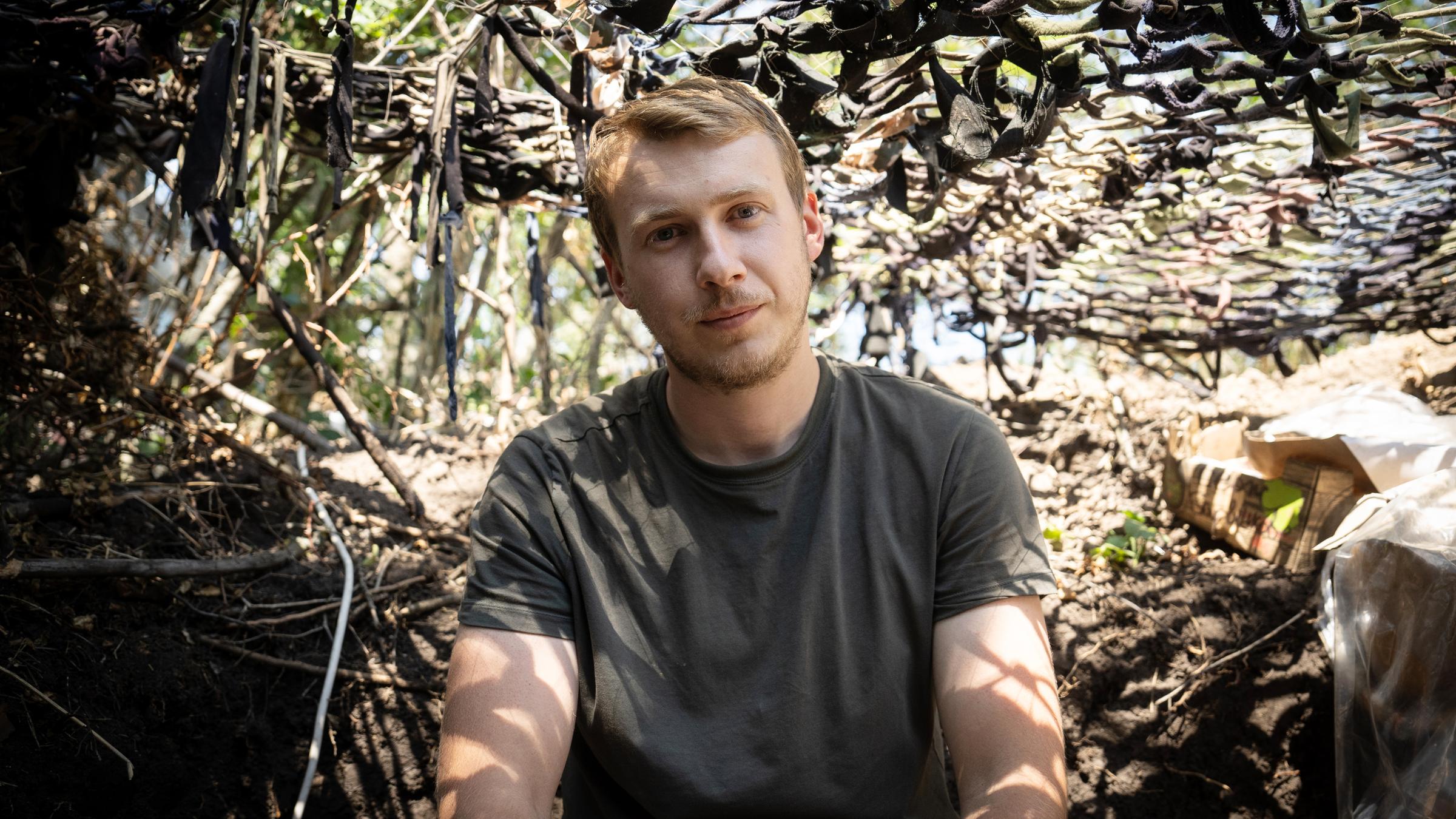 Ein Mann sitzt in einem Schützengraben.