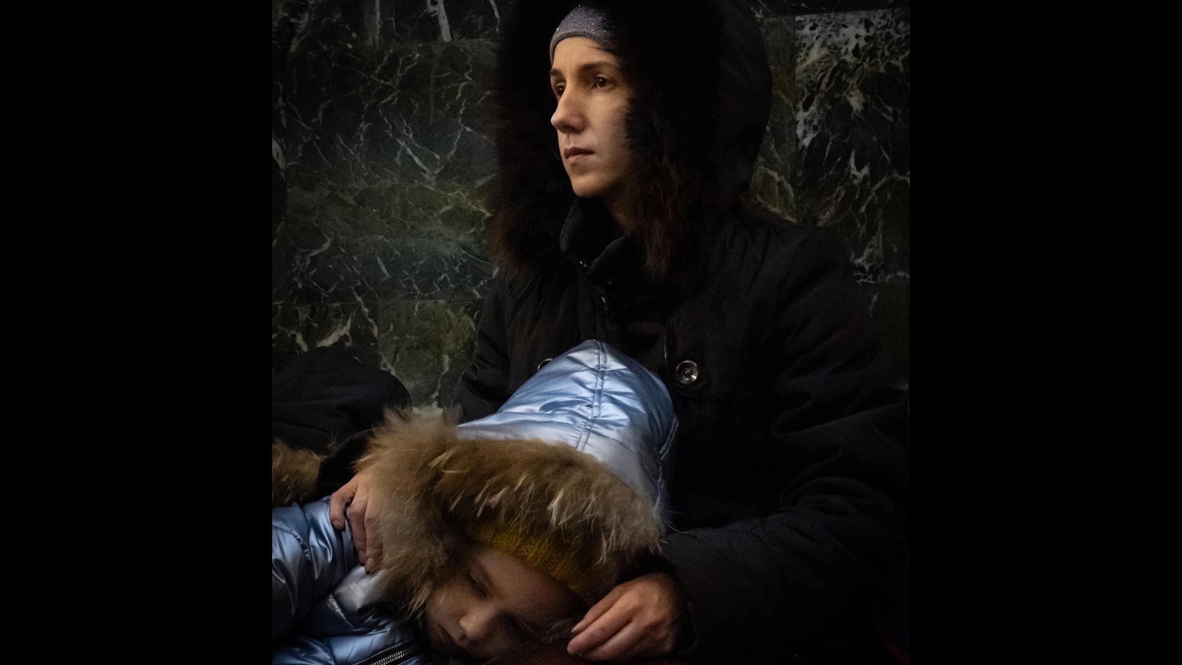 Eine Frau in dicker Jacke hält ein Kind in ihren Armen.