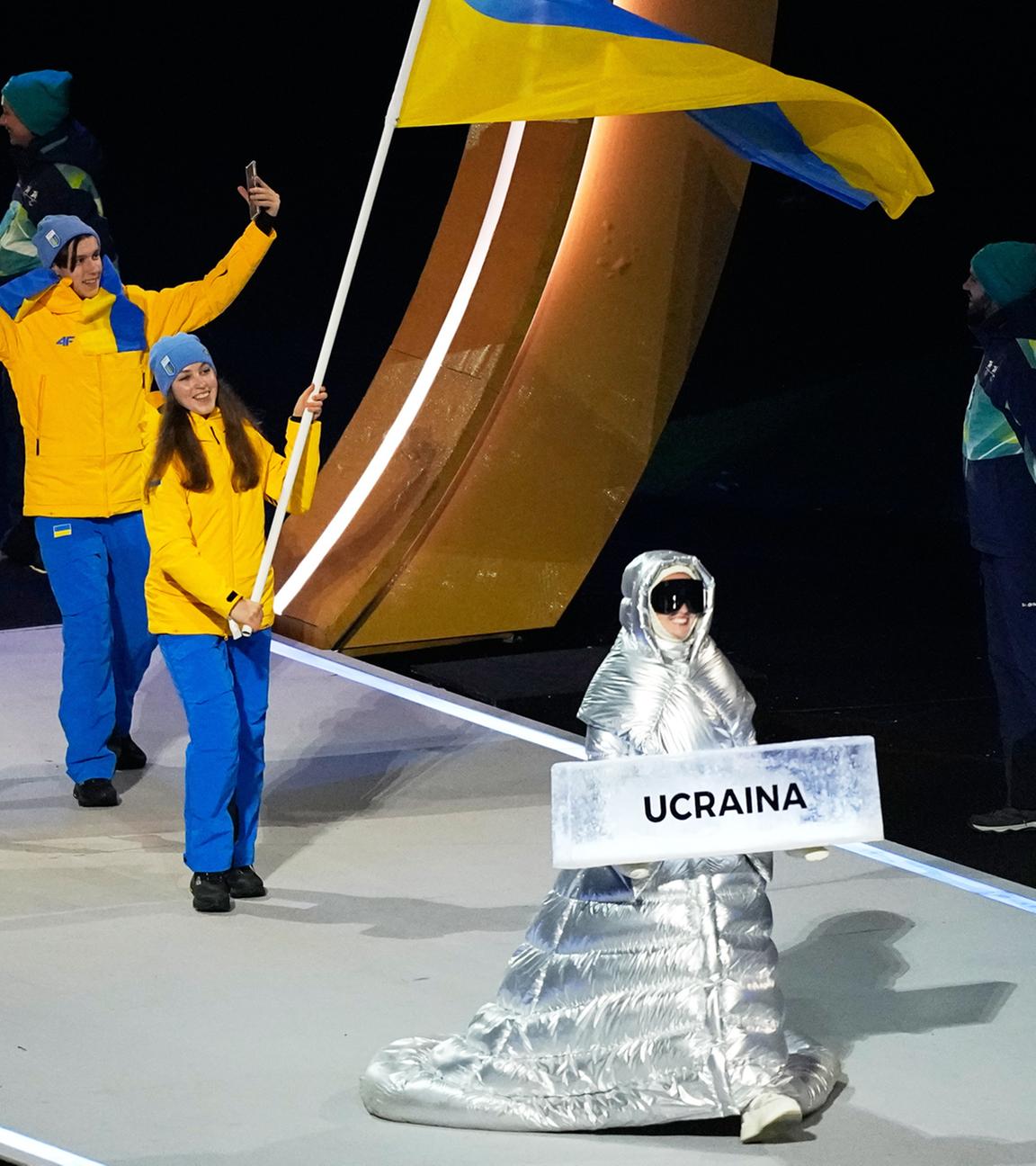 Anastasia Kutscherowa trägt das Schild, als sie die Athleten aus der Ukraine bei der Eröffnungsfeier der Olympischen Winterspiele in die Arena führt.