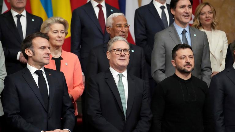  Der britische Premierminister Sir Keir Starmer (M) steht für ein Gruppenfoto der Staats- und Regierungschefs Europas zwischen Frankreichs Präsident Emmanuel Macron (l) und dem ukrainischen Präsidenten  Wolodymyr Selenskyj (r) auf dem Ukraine-Sondergipfel im Lancaster House.