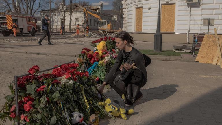 Eine Frau legt in Sumy nach einem Angriff Blumen an einem Gegendkort nieder.