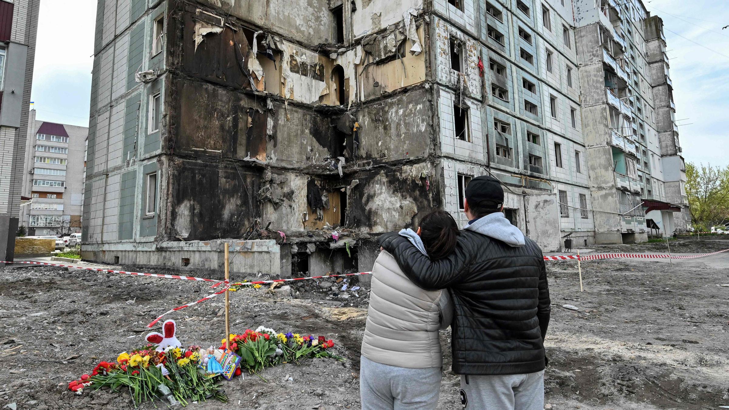 Menschen stehen vor zerstörtem Wohnhaus