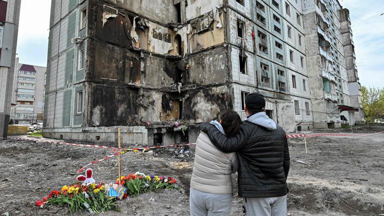 Menschen stehen vor zerstörtem Wohnhaus
