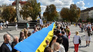 Ukrainer gehen mit der Nationalflagge durch die Stadt.
