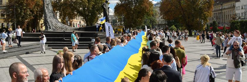 Ukrainer gehen mit der Nationalflagge durch die Stadt.