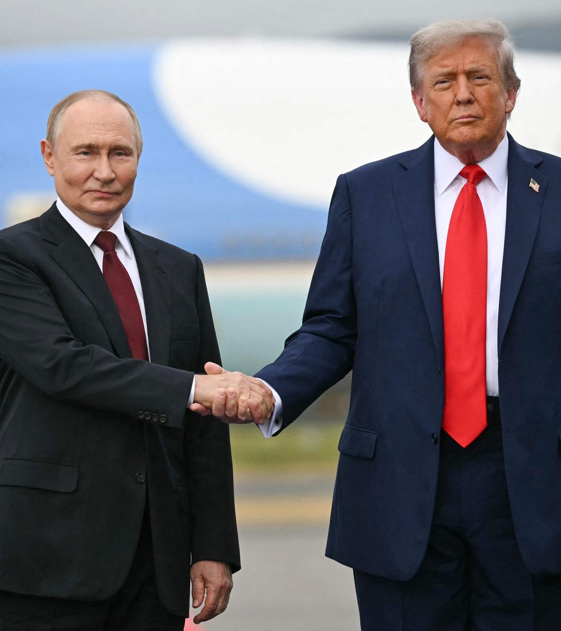 Trump und Putin geben sich die Hand und schauen in die Kamera