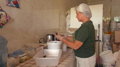 Frau in einer Suppenküche, die Gemüse schält, um sie zur Suppe zu verarbeiten.