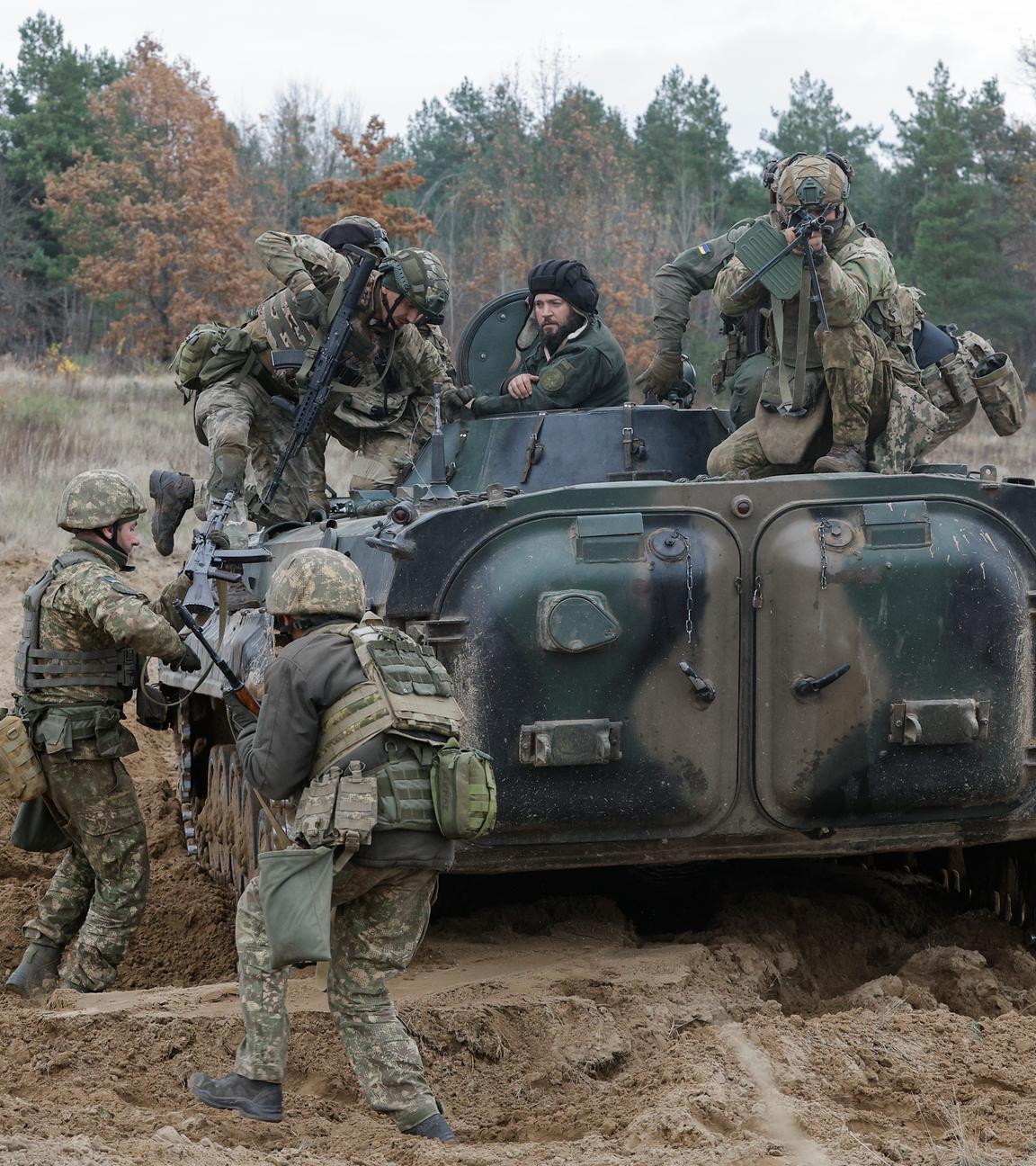 Bewaffnete Soldaten steigen auf einen Panzer auf