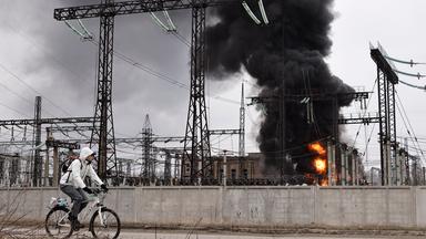 Ein Mann radelt nach einem russischen Angriff an einem Elektrizitätswerk vorbei. Dort ist ein Feuer ausgebrochen.