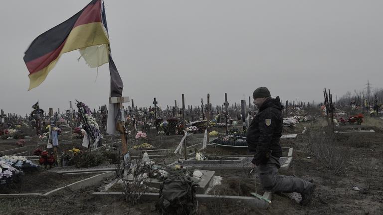 Bruder kniet am Grab von Michael P. in der Ukraine