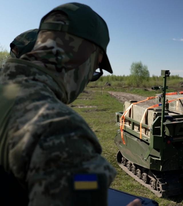 Ukrainische Soldaten lenken ferngesteuerten Kampfroboter am Boden.