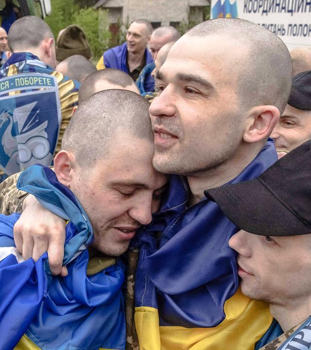 Freigelassene ukrainische Kriegsgefangene umarmen sich nach einem Gefangenenaustausch an einem nicht genannten Ort in der Region Tschernihiw am 15. Mai 2026.
